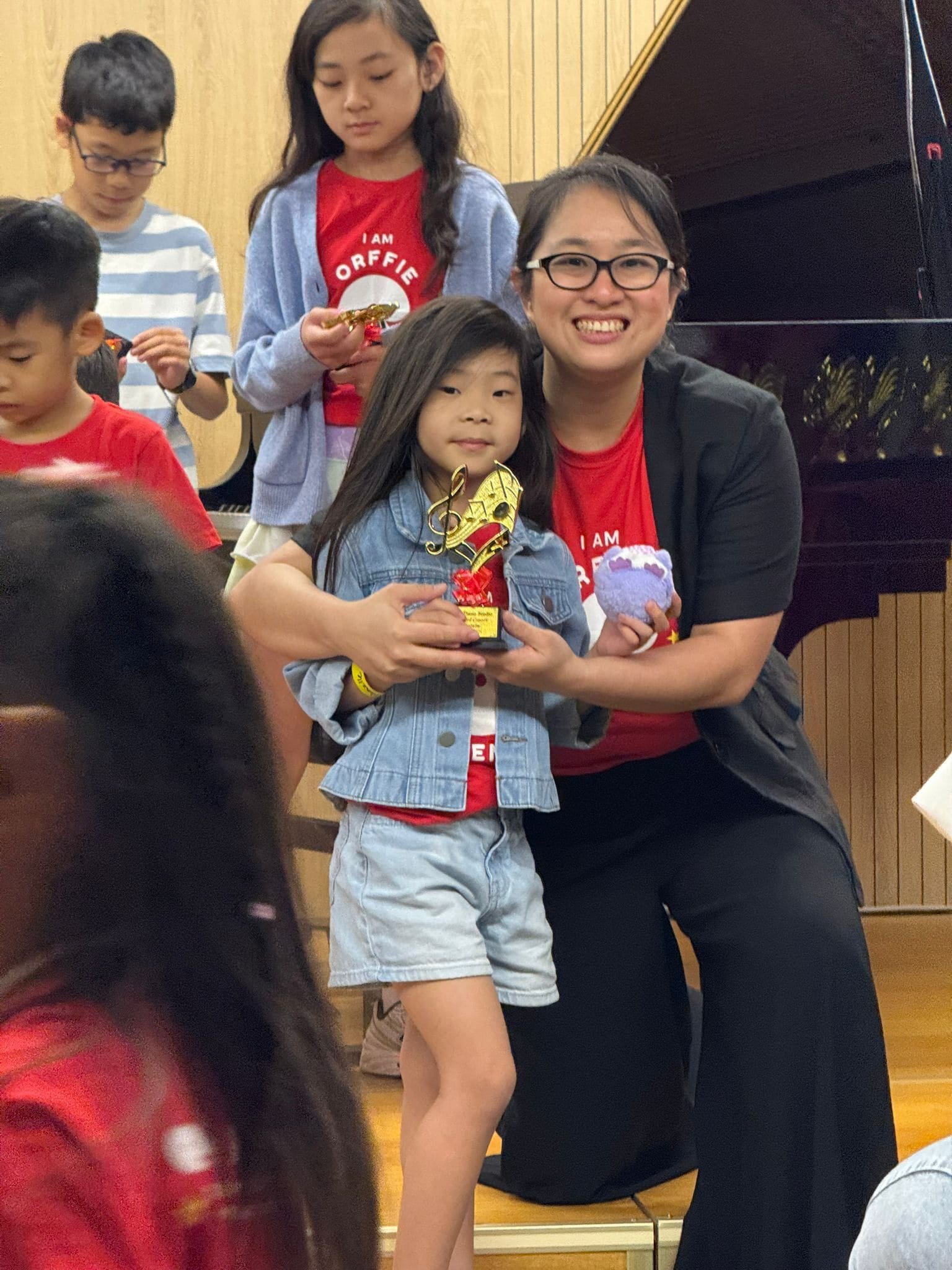 Gail, Founder and Piano Teacher at Gail's Piano Studio Bukit Timah with a student holding a recital trophy