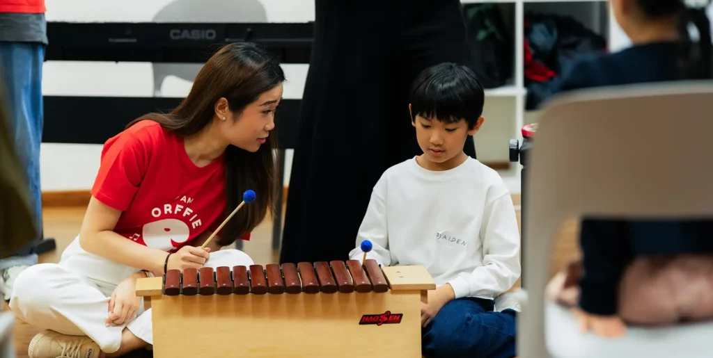 Young child smiling while playing the piano during a lesson in Singapore